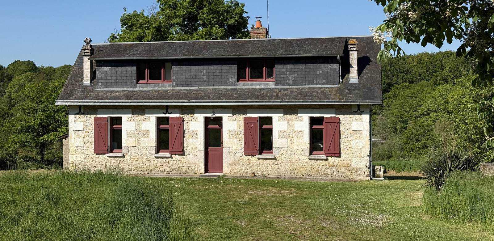 Le Gîte d'Anouck en entier, maison de garde-chasse en tuffeau aux volets bordeaux dans son pré