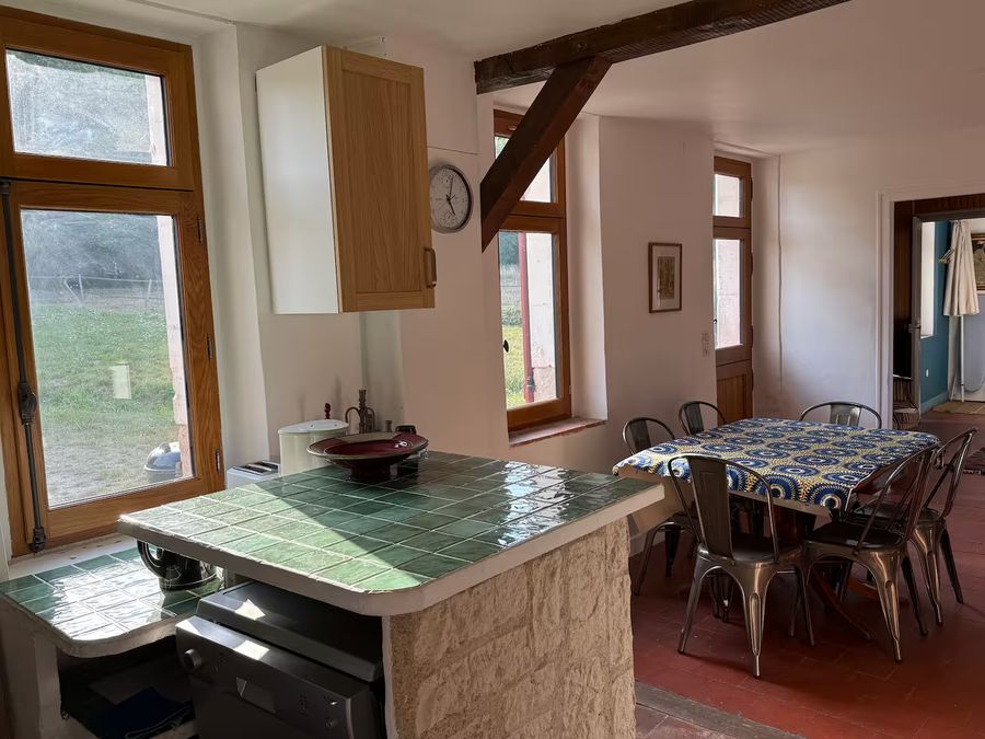 Salle à manger du gîte ouverte sur la cuisine, tomettes au sol